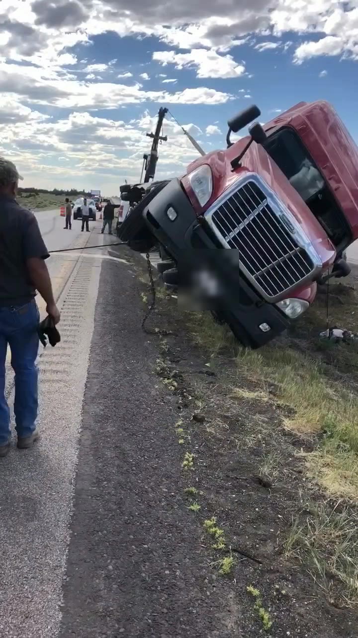 The tractor coming up off its side, wrecker booms in the background